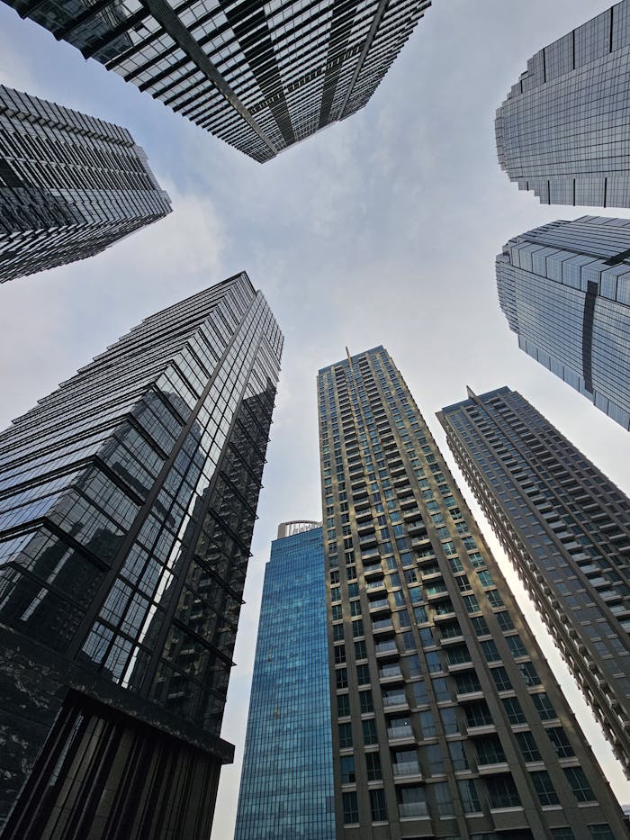 why-choose-us Upward view of Jakarta skyscrapers against a blue sky, showcasing modern architecture.
