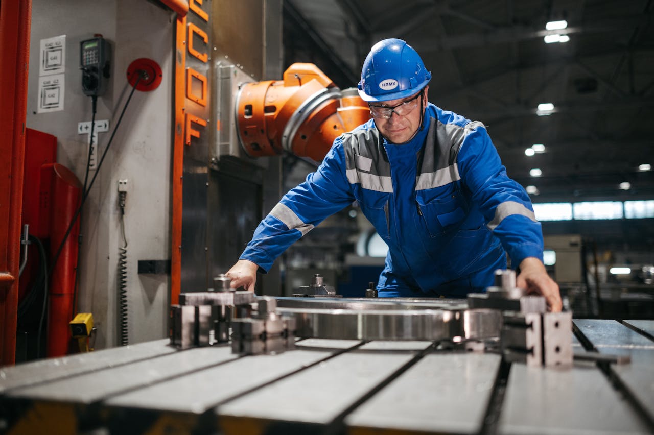 gallery-6 Male worker in blue uniform operates machinery in an industrial factory setting, showcasing engineering and industry.